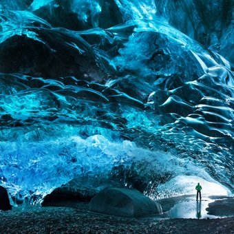 Man stands inside ice cave in Iceland