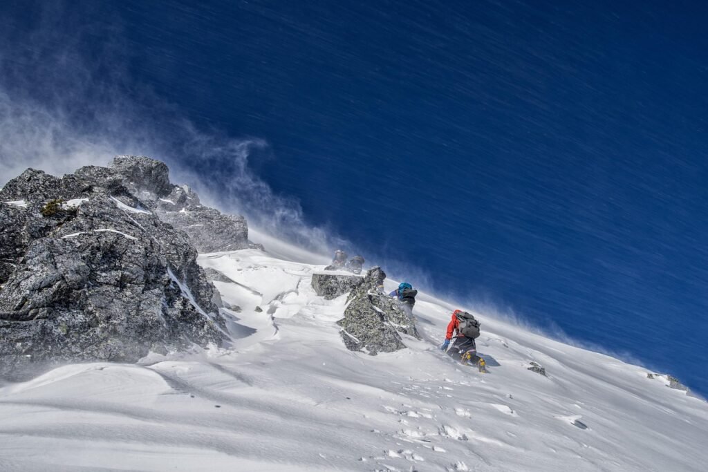 Two people climb a snowy mountain