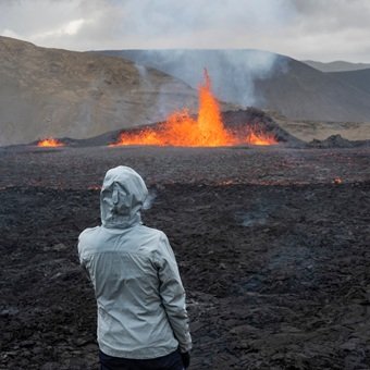 Woman looks at lava in active volcano